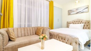 Une chambre d’hôtel avec un lit, un canapé, une table basse et un tableau au mur.