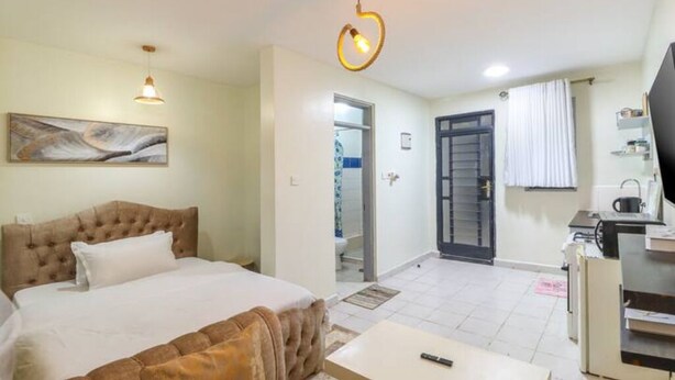 Une chambre d’hôtel avec un lit, un bureau, une chaise, une télévision et un tableau au mur.