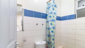Une salle de bain avec des toilettes, un rideau de douche et un miroir.