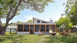 A modern house with a large porch, wooden deck, and outdoor seating.