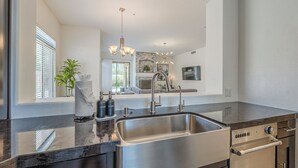 A modern kitchen with a stainless steel sink, a built-in oven, and a countertop with a marble-like finish. - Greyhawk - Pool - Chef's Kitchen - Golfer's Dream Location (Scottsdale)