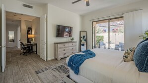 A bedroom with a bed, a ceiling fan, a TV, a dresser, and a view of the outside. - Greyhawk - Pool - Chef's Kitchen - Golfer's Dream Location (Scottsdale)