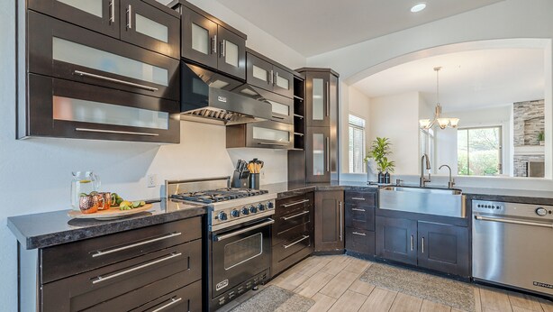 A modern kitchen with dark cabinetry, stainless steel appliances, and a central island. - Greyhawk - Pool - Chef's Kitchen - Golfer's Dream Location (Scottsdale)