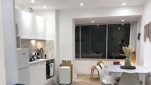 A compact hotel room with a bed, a small kitchenette, a dining area with a table and chairs, and a large window. - Waterfront studio with enchanting views (Six-Fours-les-Plages)