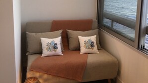 A cozy room with a sofa, decorative wall mirrors, a view of the sea, and a small table with a candle. - Waterfront studio with enchanting views (Six-Fours-les-Plages)