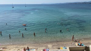 A beach with clear water, people swimming and sunbathing, and boats in the distance. - Waterfront studio with enchanting views (Six-Fours-les-Plages)