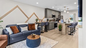 Una sala de estar moderna con un sofá, una mesa de centro y taburetes de bar.