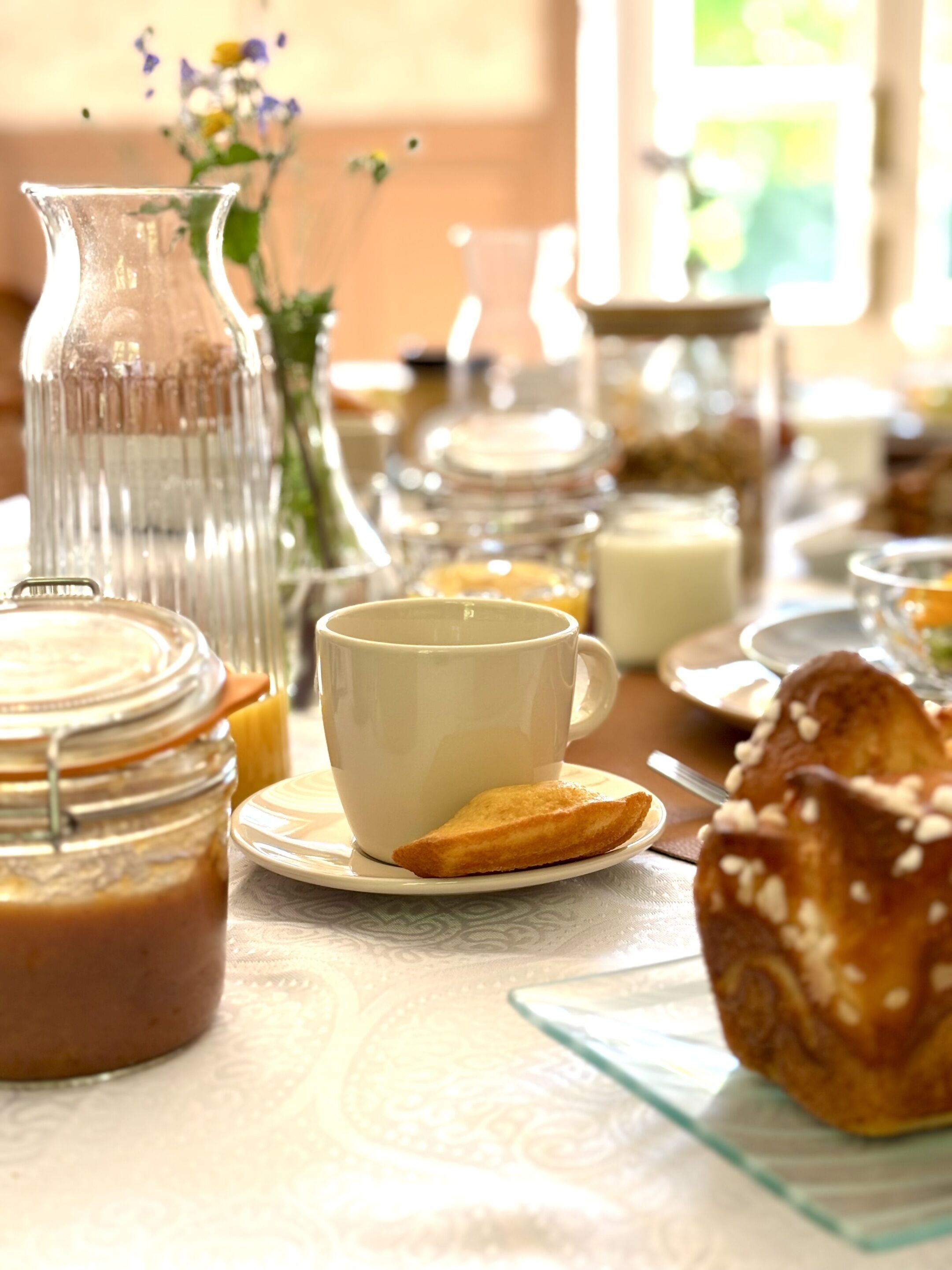 Et morgenbord med kaffekop, bagværk og en kande på et bord.