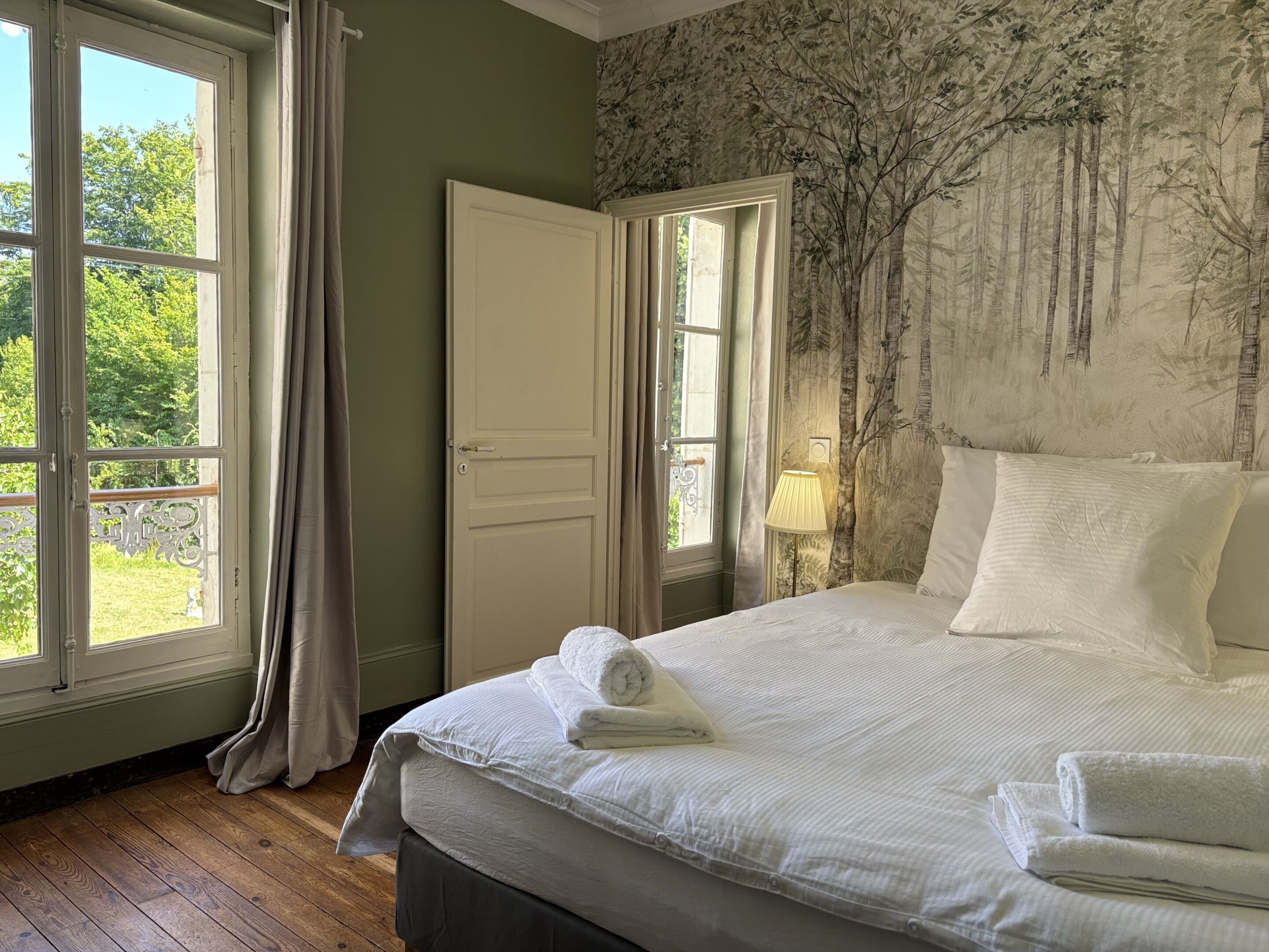 Un dormitorio con una cama grande, una puerta y dos ventanas.