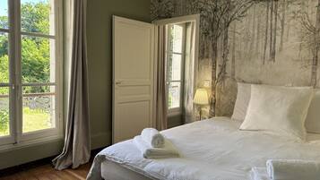 Un dormitorio con una cama grande, una puerta y dos ventanas.