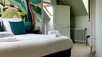 Un dormitorio con cama, un mural colorido, un tragaluz y vista a un pasillo.