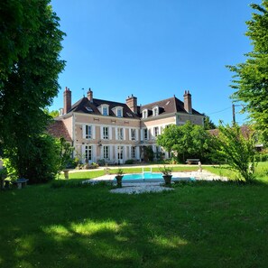 Una casa grande de dos pisos con una piscina en el jardín delantero.