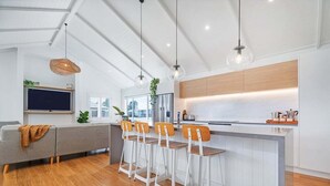 A modern kitchen with a central island, bar stools, and pendant lighting.