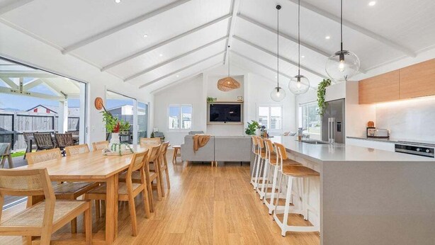 A spacious kitchen with a large island, wooden dining table, and bar stools.