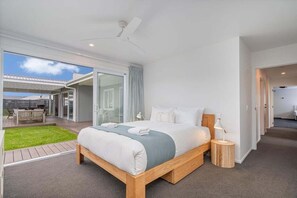 Ein modernes Hotelzimmer mit einem großen Bett, einem kleinen Nachttisch, einem Deckenventilator und Blick auf die Terrasse.