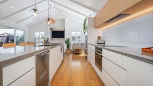 A modern kitchen with a central island, wooden flooring, and pendant lighting.