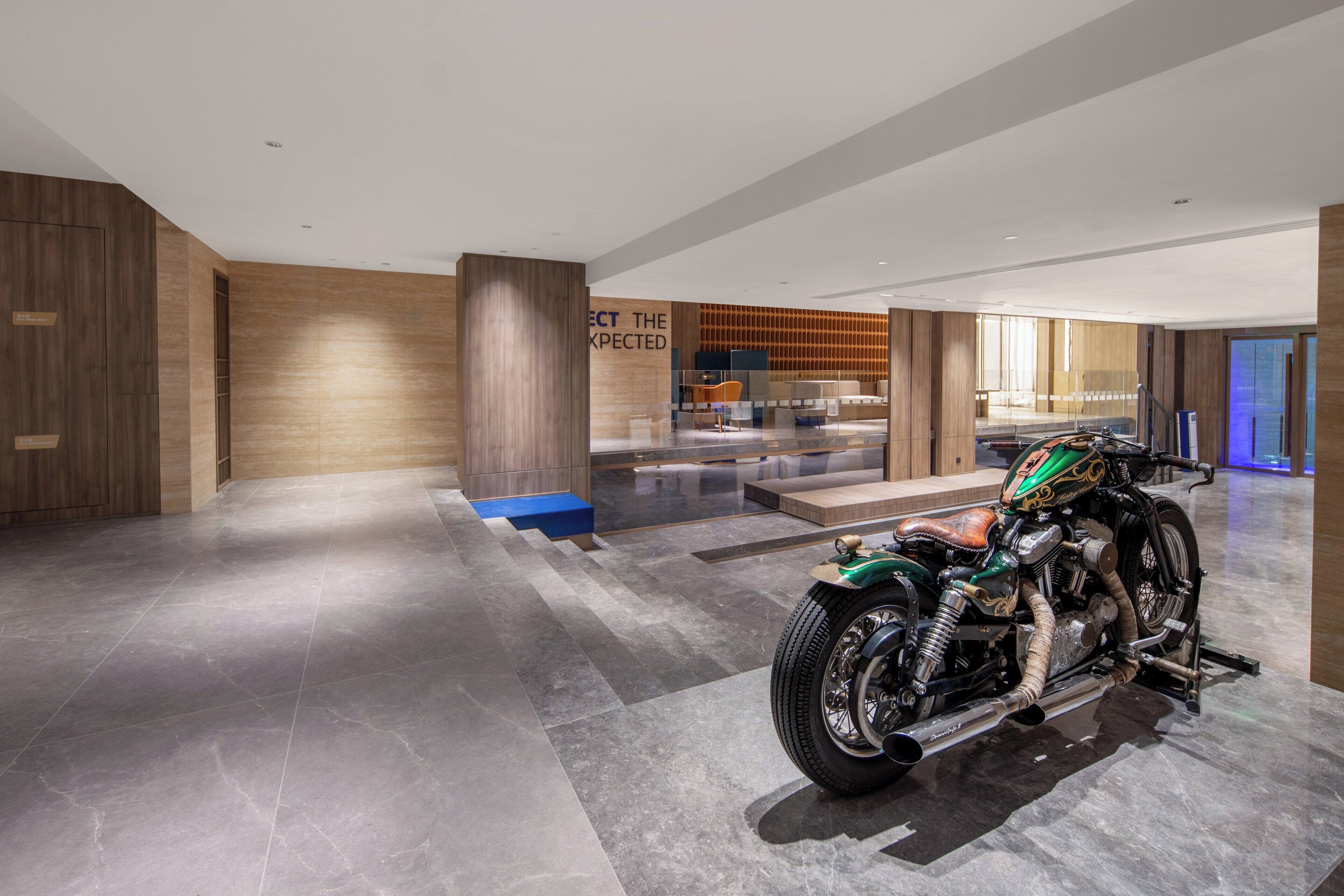 Un interior moderno con una motocicleta, paneles de madera y un letrero que dice 'EXPECT THE EXPECTED'.