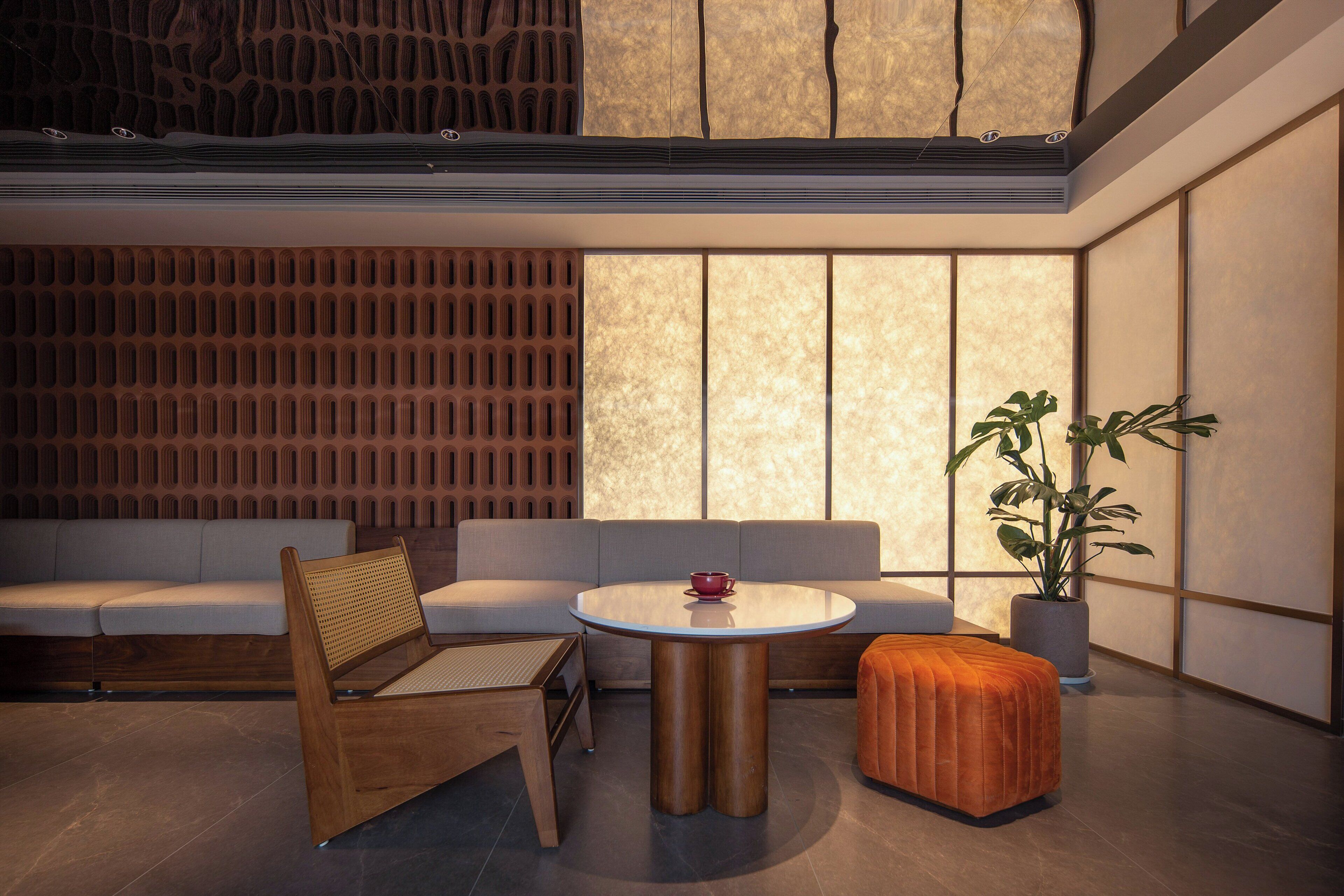 A modern interior with a wooden bench, a round table, and a sofa.