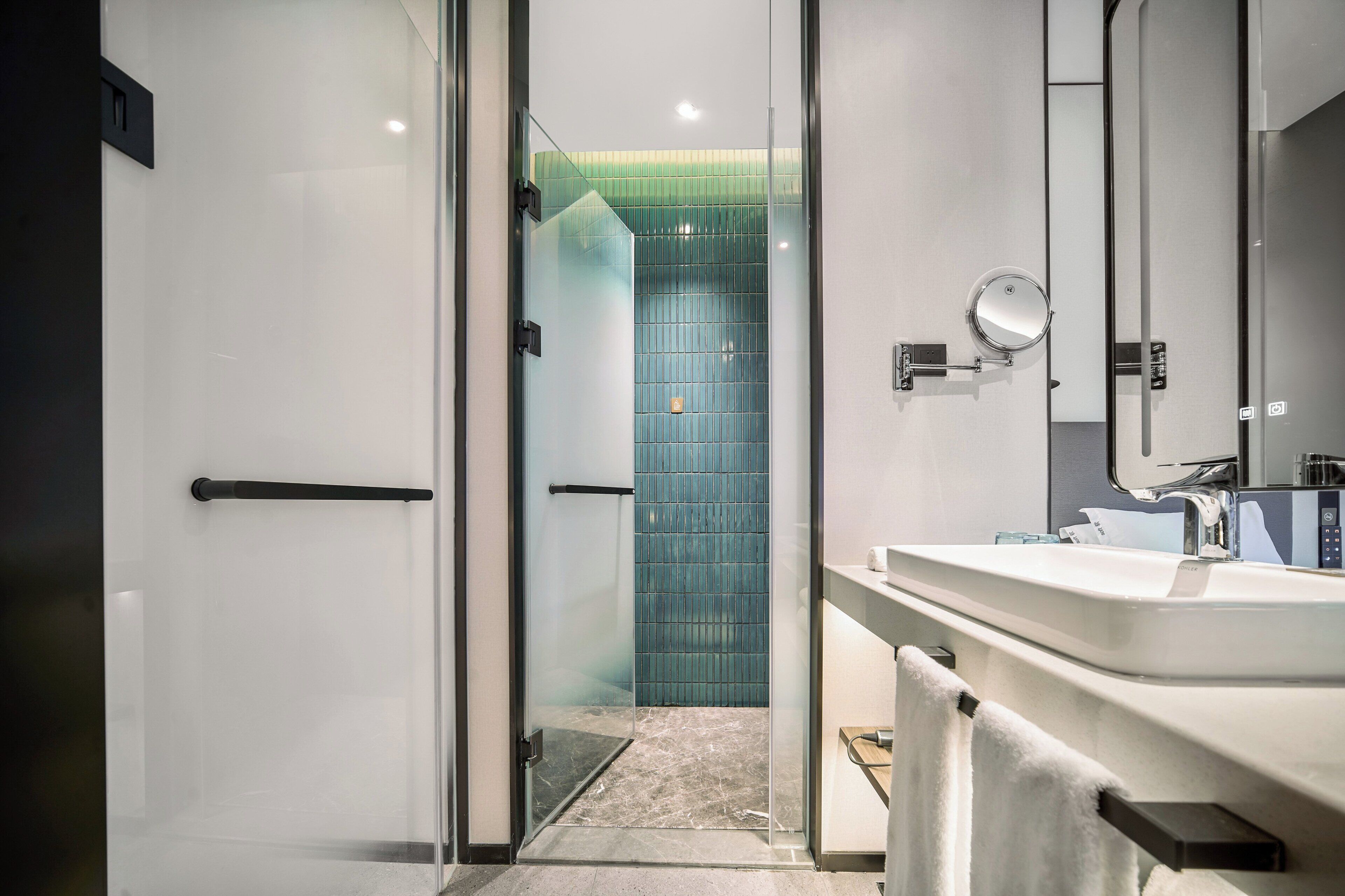 A modern bathroom with a glass shower enclosure, a white sink, and a mirror.