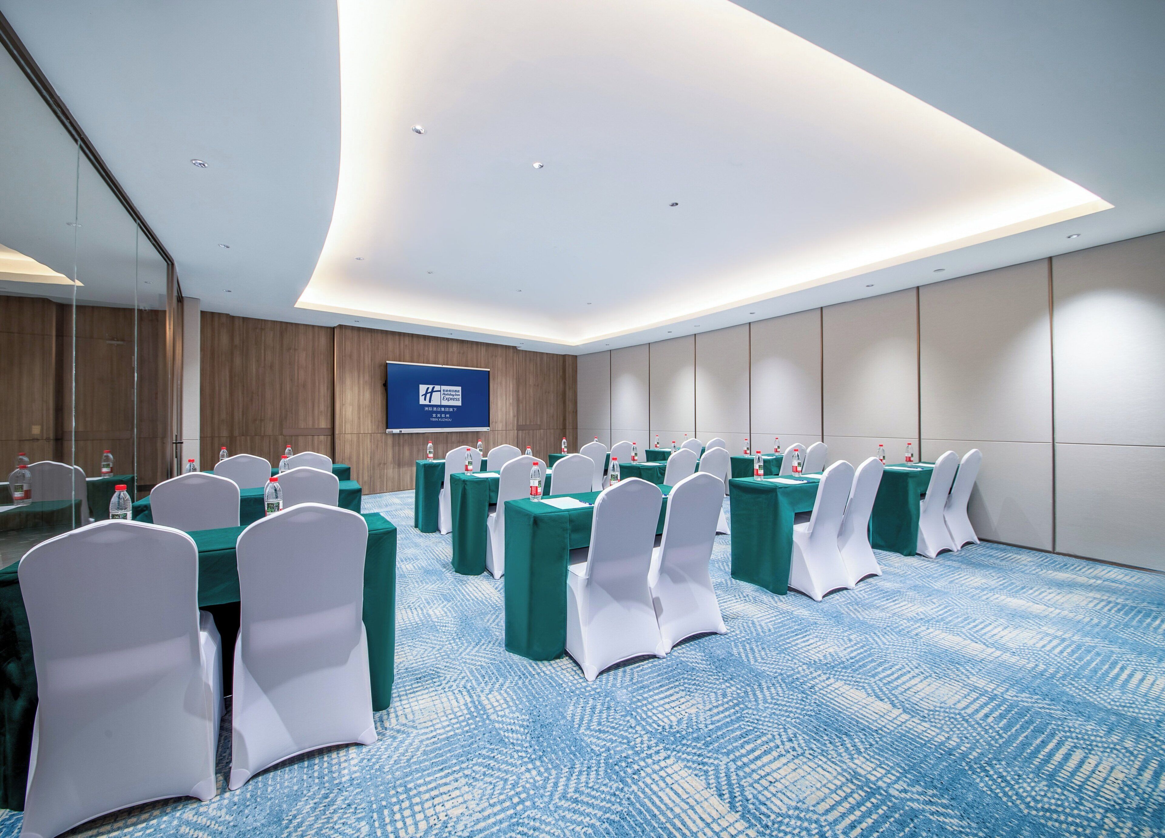 A conference room with tables, chairs, and a screen.