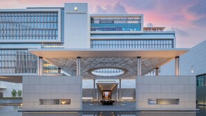 A modern building with a glass facade, a covered entrance, and a reflective pool. - InterContinental Yining by IHG (Yining)