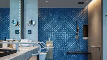 A modern bathroom with a blue patterned wall, a large mirror, a handheld showerhead, and a towel rack.