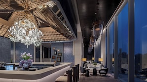 A modern hotel lobby with a central reception desk, seating area with sofas and chairs, a large chandelier, and a view through large windows. - InterContinental Yining by IHG (Yining)
