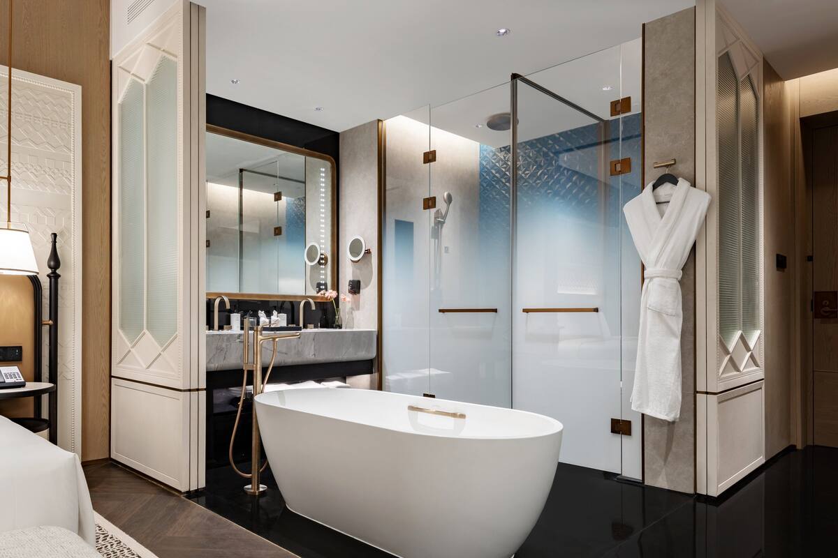 A modern bathroom with a freestanding bathtub, a glass-enclosed shower, and a vanity with a mirror.