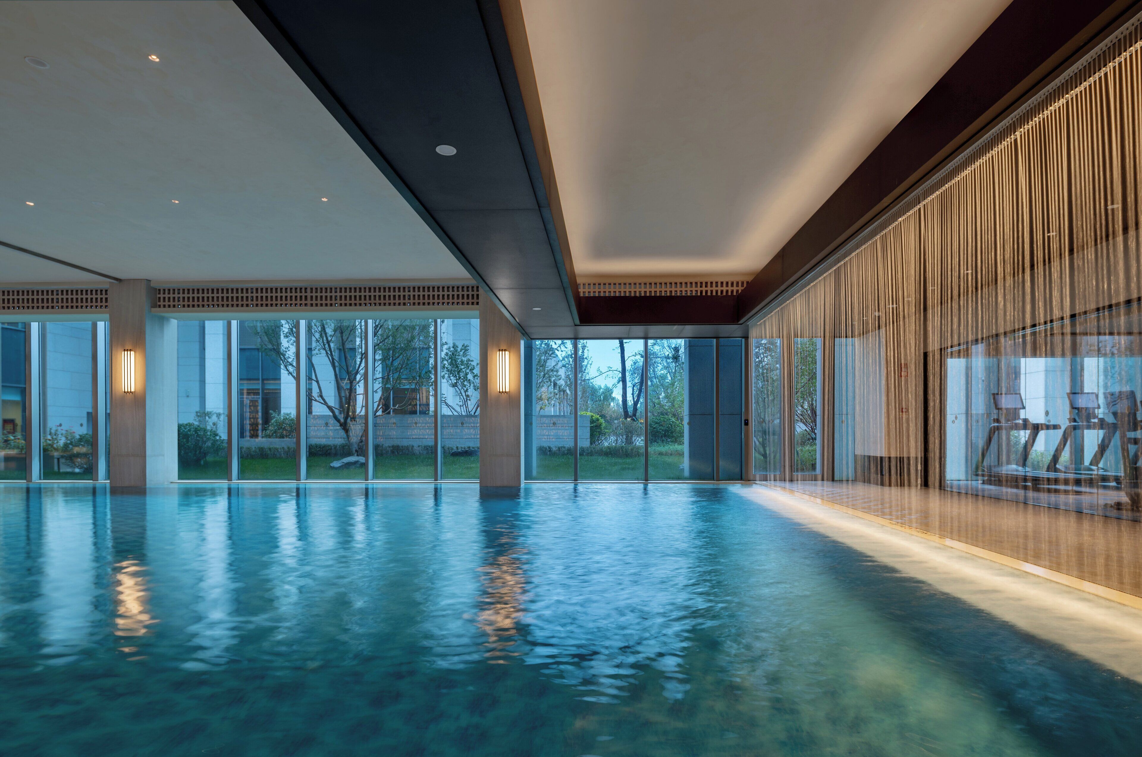 Une vaste piscine intérieure dotée de parois en verre transparent, offrant une vue sur l’extérieur.