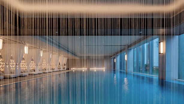 An indoor swimming pool with a clear water surface, a ceiling with vertical lines, and a row of lights along the pool's edge. - InterContinental Yining by IHG (Yining)