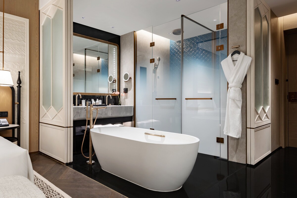 A modern bathroom with a freestanding bathtub, a glass-enclosed shower, and a vanity with a mirror.