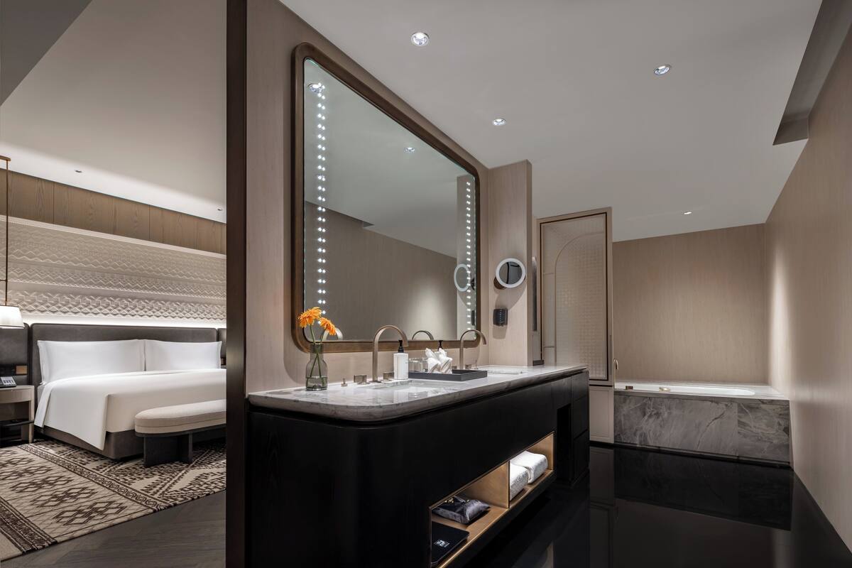 A modern bathroom with a large mirror, vanity, and bathtub.