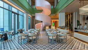 A modern hotel lobby with a spiral staircase, seating areas, and a bar. - EVEN Hotel Yining by IHG (Yining)