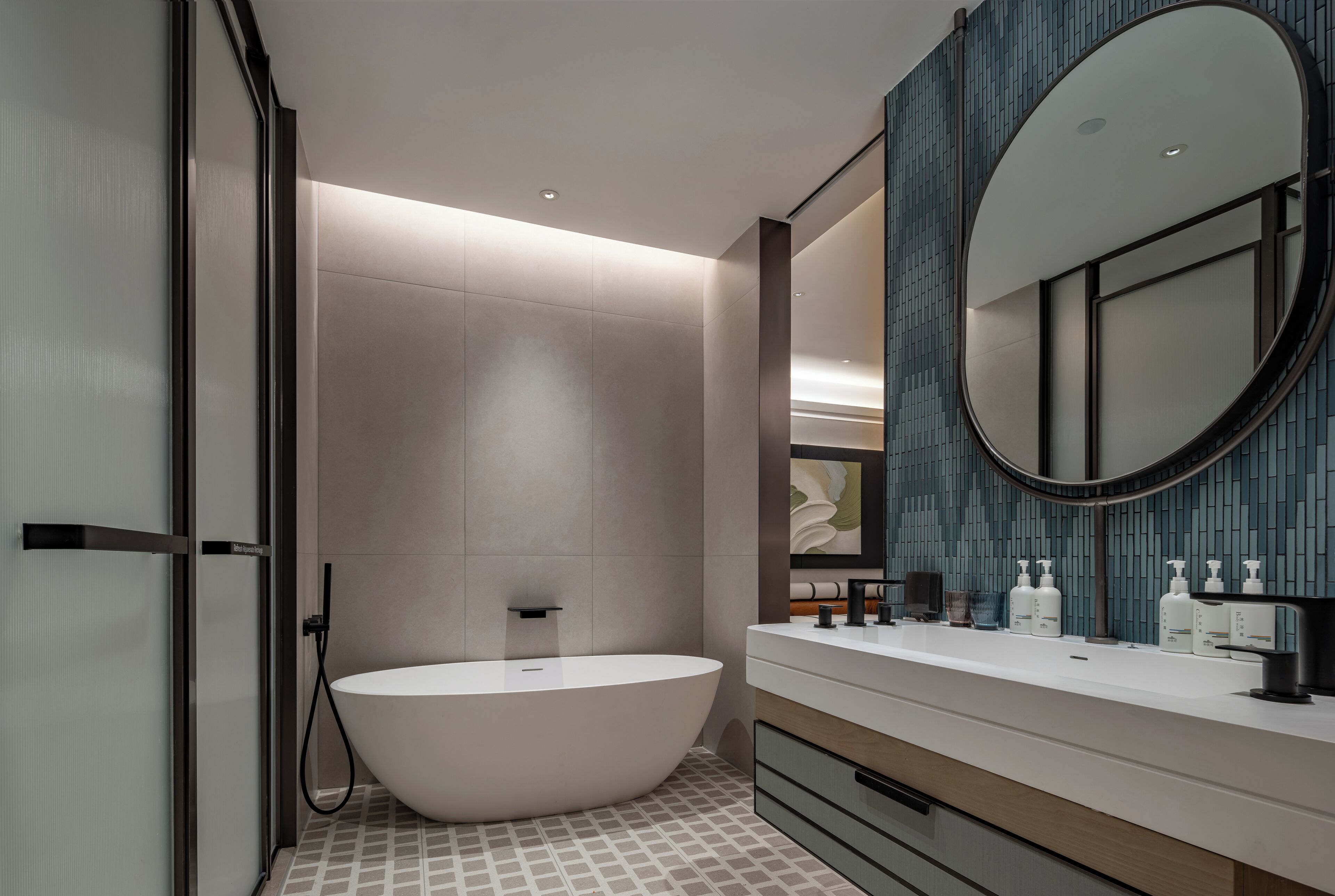 A modern bathroom with a freestanding bathtub, a large mirror, and a vanity with toiletries.