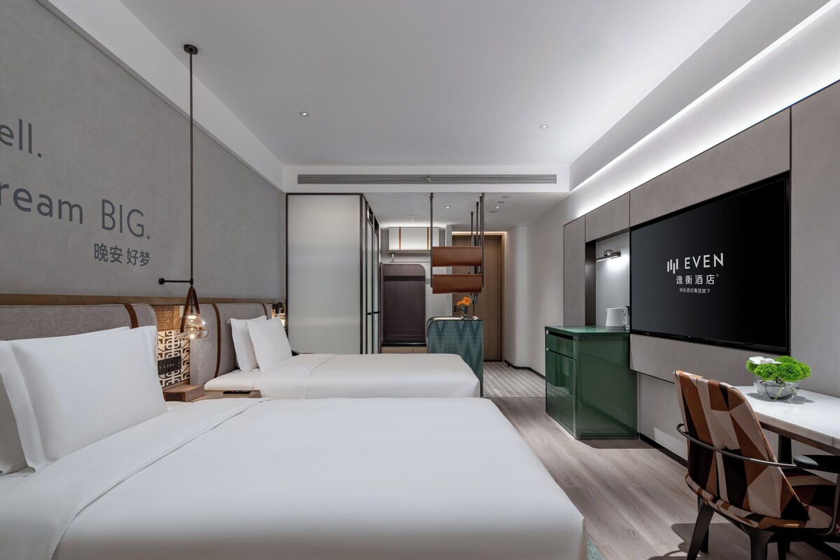 Une chambre d’hôtel moderne avec un grand lit, un bureau et une télévision.