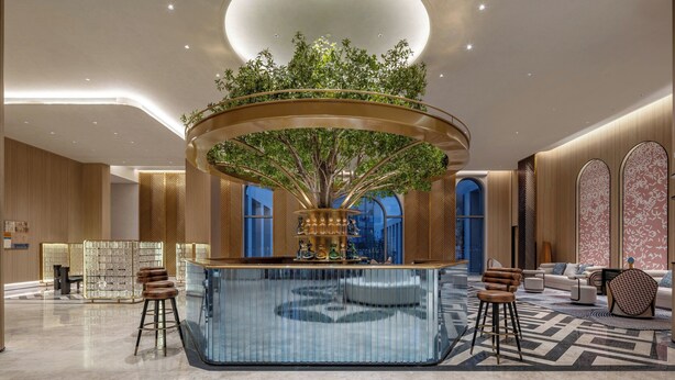 A modern lobby with a central circular bar, a large tree, and a seating area with bar stools. - EVEN Hotel Yining by IHG (Yining)