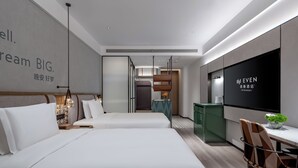 A modern hotel room with a large bed, a desk with a chair, a TV, and a small plant. - EVEN Hotel Yining by IHG (Yining)