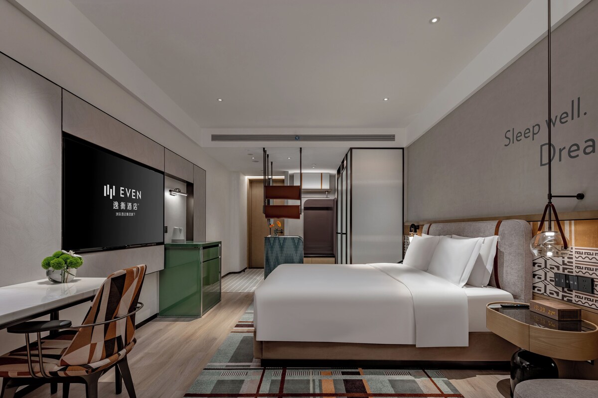 Une chambre d’hôtel moderne équipée d’un lit, d’un bureau et d’une télévision.