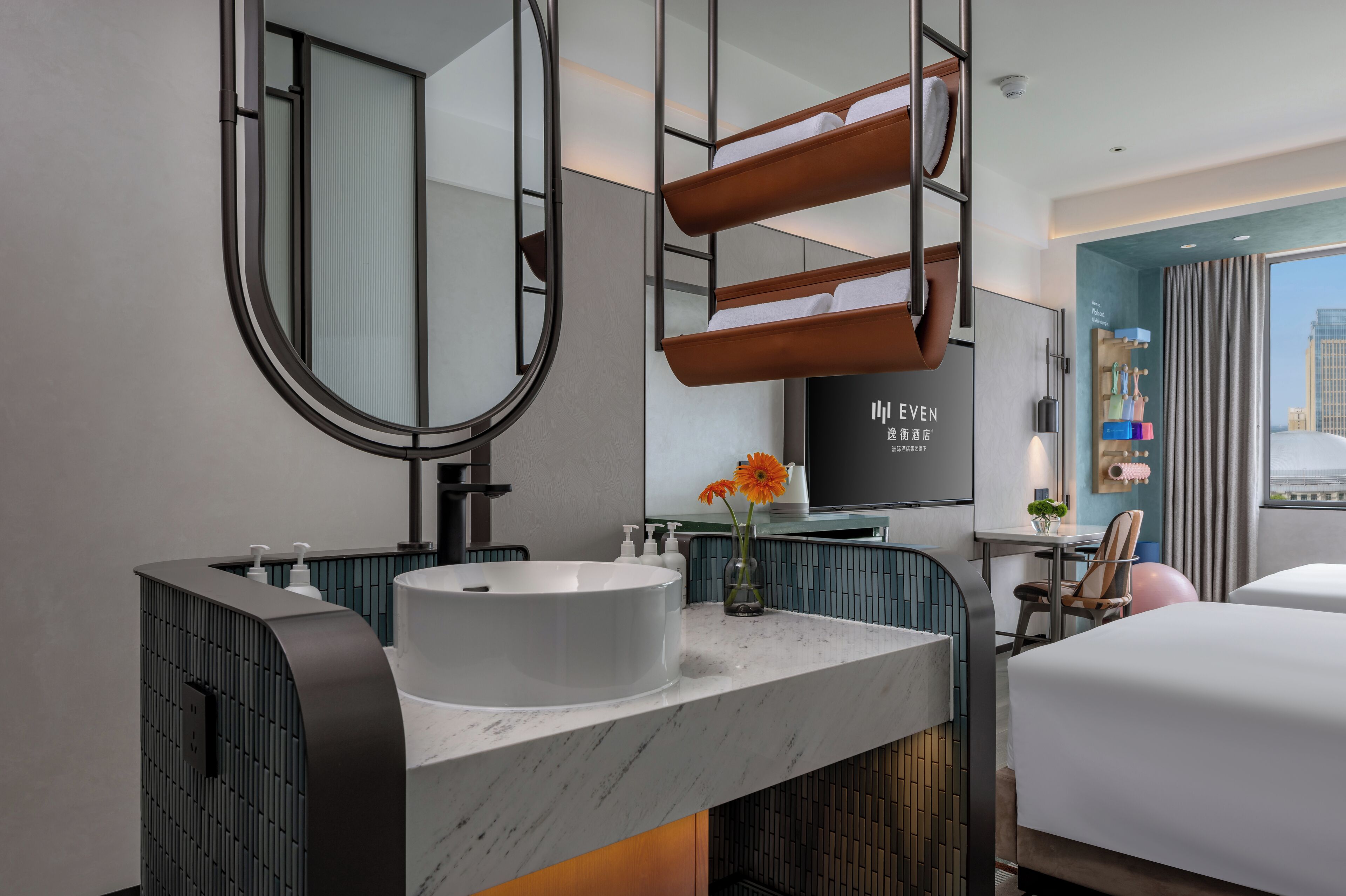A modern hotel bathroom with a large mirror, a white sink, and a towel rack.