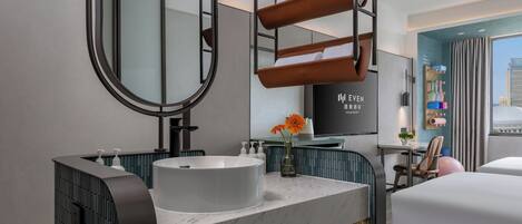 A modern hotel bathroom with a large mirror, a white sink, and a towel rack.