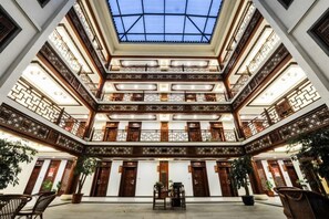 A multi-level atrium with a glass ceiling, wooden balconies, and potted plants. - Wenyuan Shanzhuang Holiday Hotel (Xuancheng)