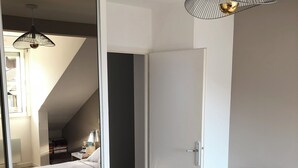 A bedroom with a bed, a bedside table with a lamp, a wardrobe, and a hanging light fixture. - Top-floor cross-through apartment with 2 terraces, in Divonne-les-Bains (Divonne-les-Bains)