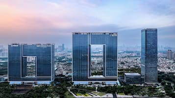 Tres edificios altos con fachadas de vidrio reflectante, rodeados de vegetación y una masa de agua.