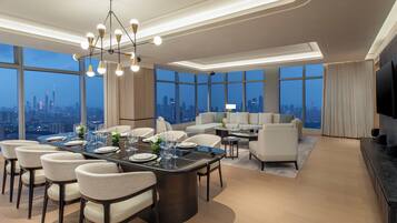 A modern hotel room with a dining area, a sofa set, and a TV.