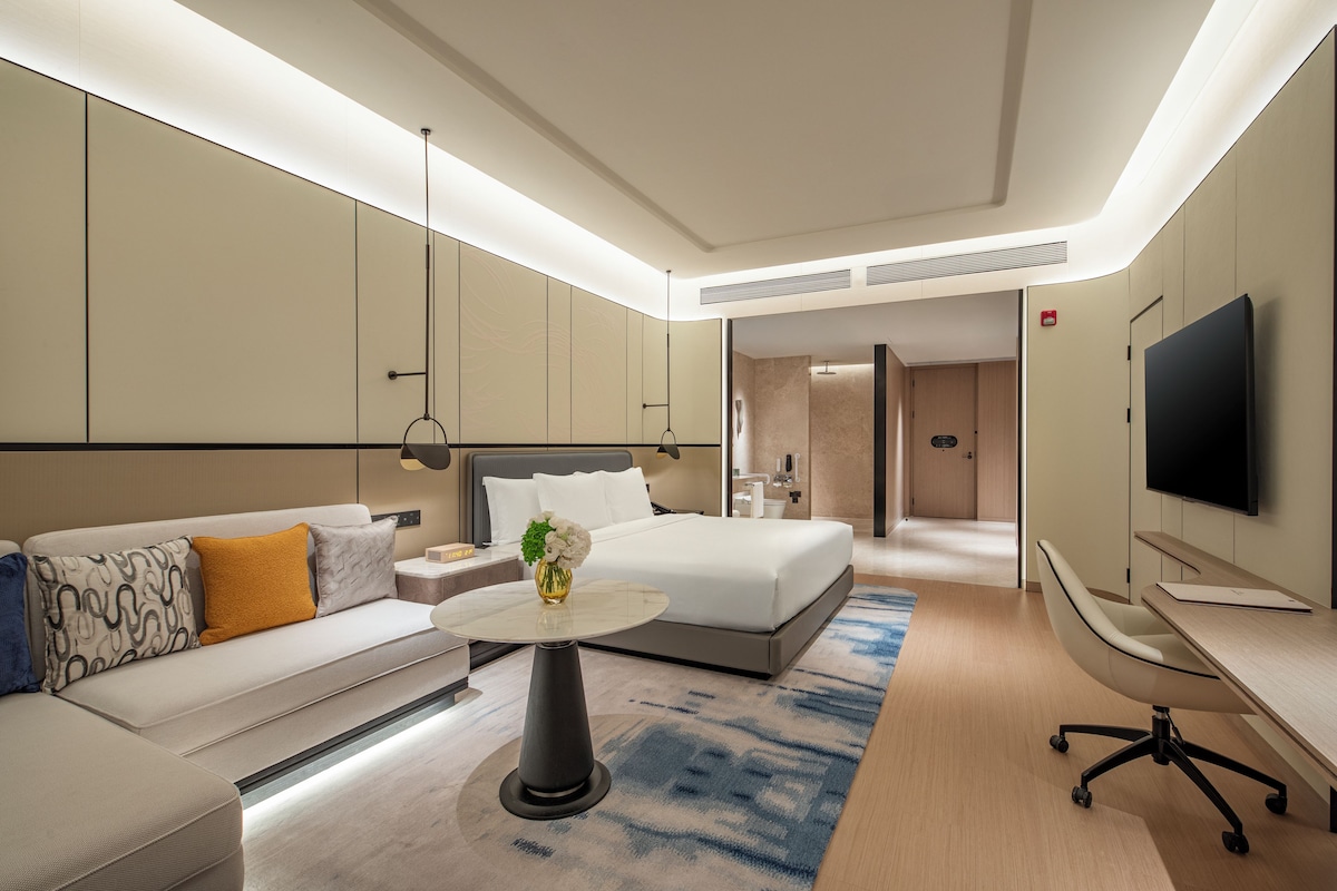 Une chambre d’hôtel moderne équipée d’un lit, d’un canapé, d’un bureau et d’une télévision.