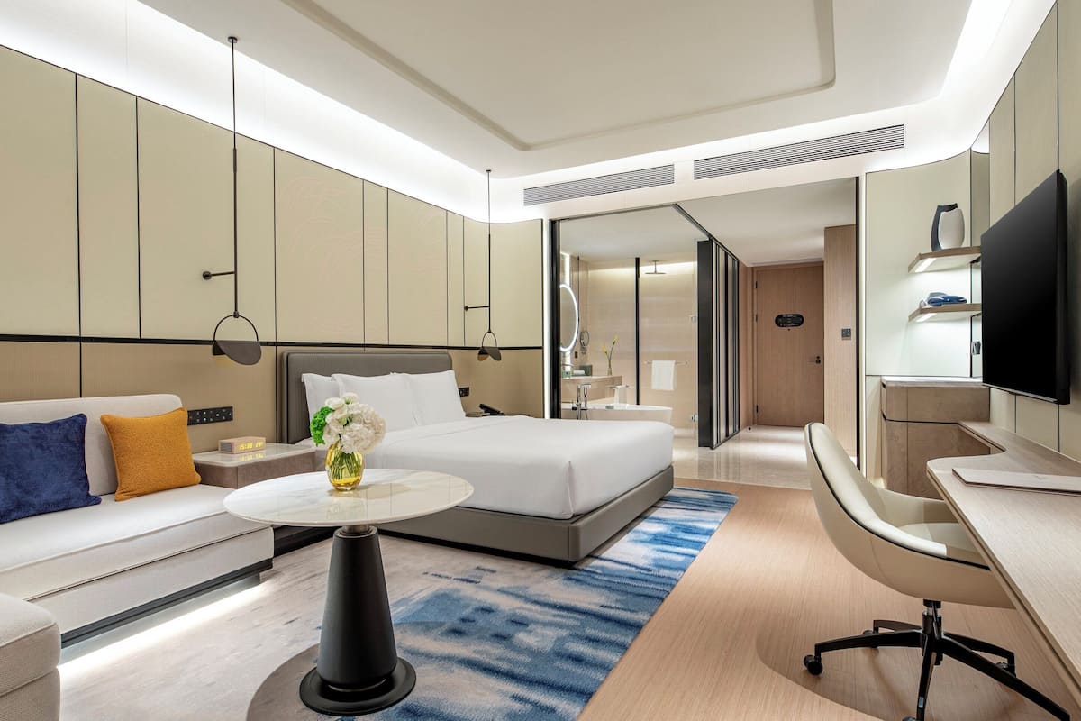 Ein modernes Hotelzimmer mit Bett, Sofa, Schreibtisch und Fernseher.