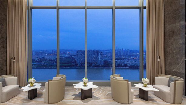 A modern lounge with a panoramic city view, featuring a curved sofa set and a marble-patterned floor. - Crowne Plaza Guangzhou Window Of Canton by IHG (Guangzhou)