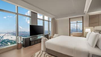 Una camera d'hotel moderna con un grande letto, una TV a schermo piatto, vista sulla città e un ponte urbano.