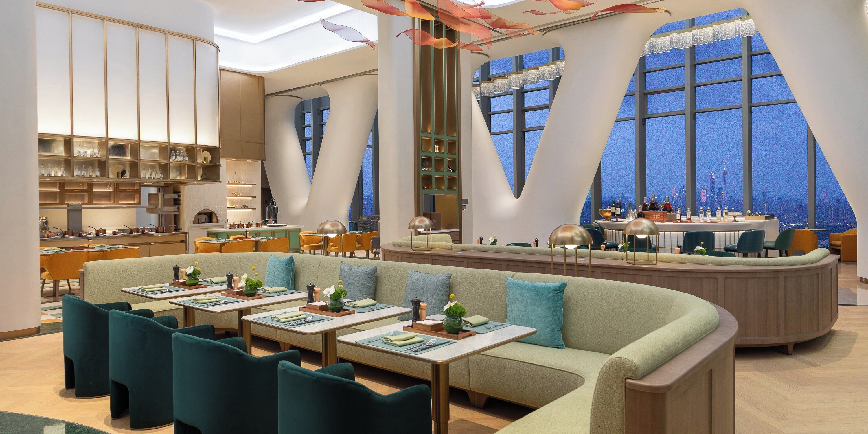 Un restaurante moderno con zona de estar central, bar y amplios ventanales con vistas a la ciudad.