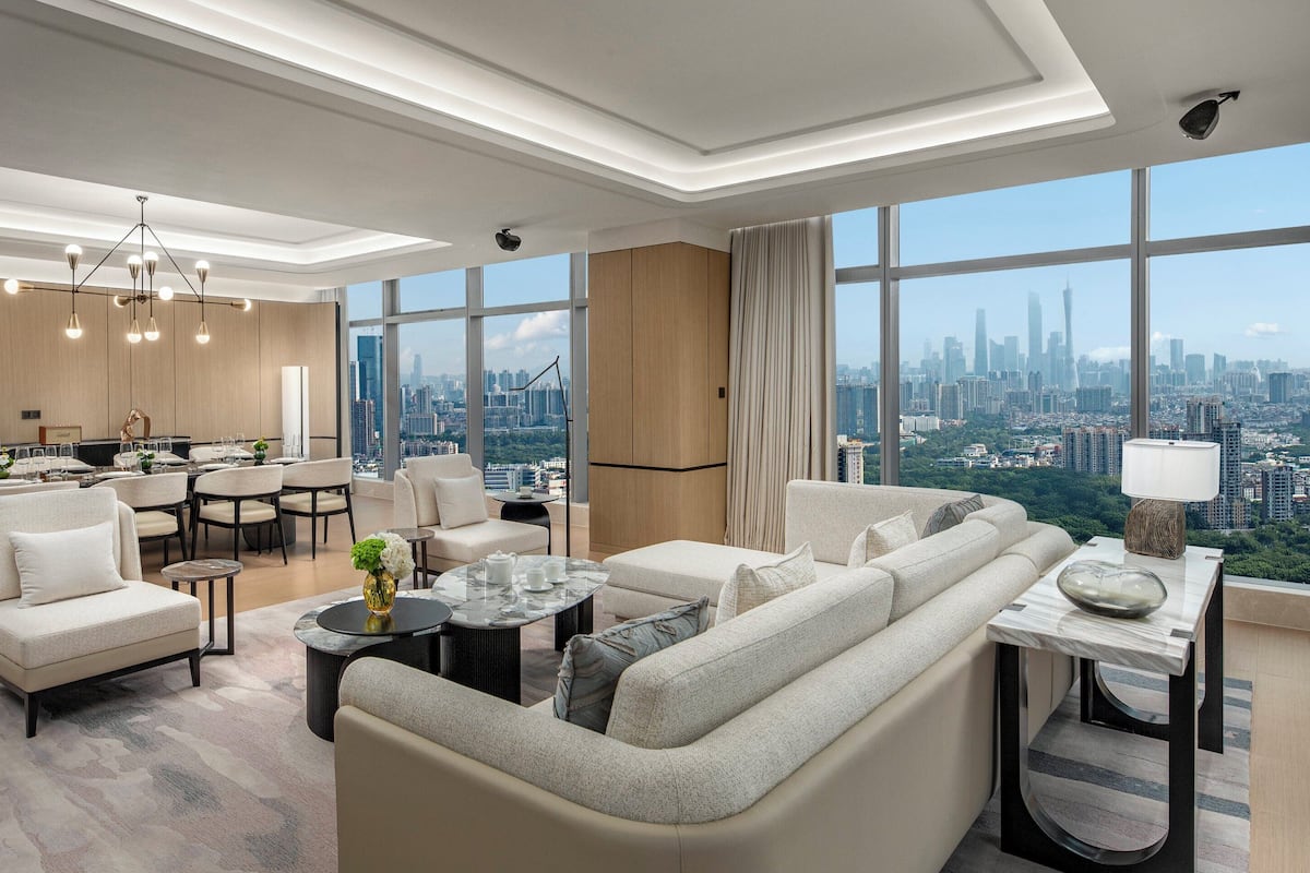 Ein modernes Hotelzimmer mit Blick auf die Stadt, einem Essbereich und einer Wohnfläche mit Sofa und Couchtisch.